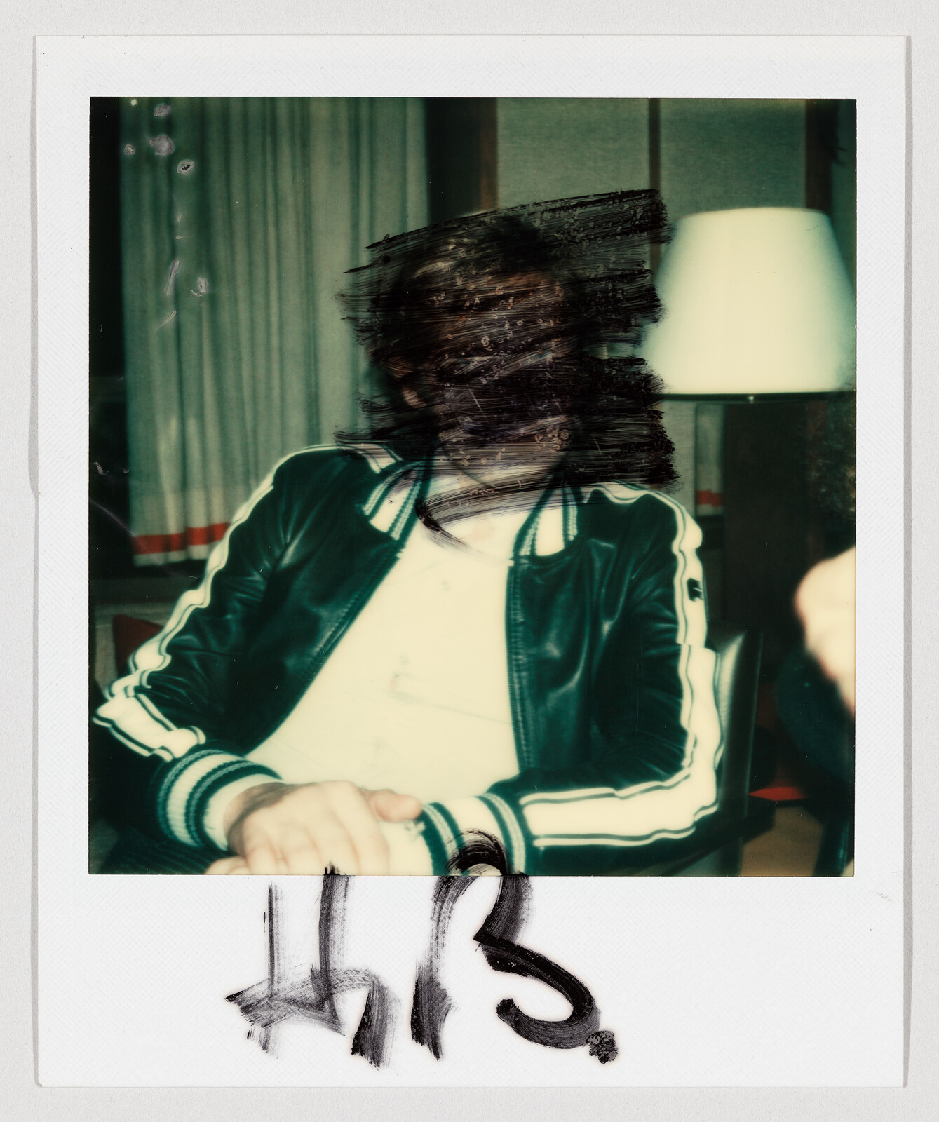 Man wearing striped-sleeve jacket sits with face scratched out and "HIS" scrawled below.