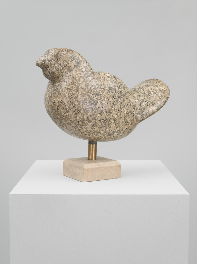 A speckled stone bird sculpture rests on a small metal rod and square base pedestal.