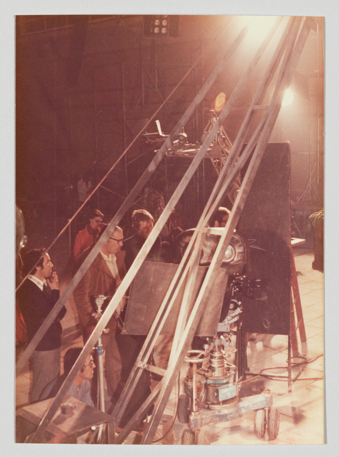 Film crew adjusts a large camera and lighting rig on a studio set.
