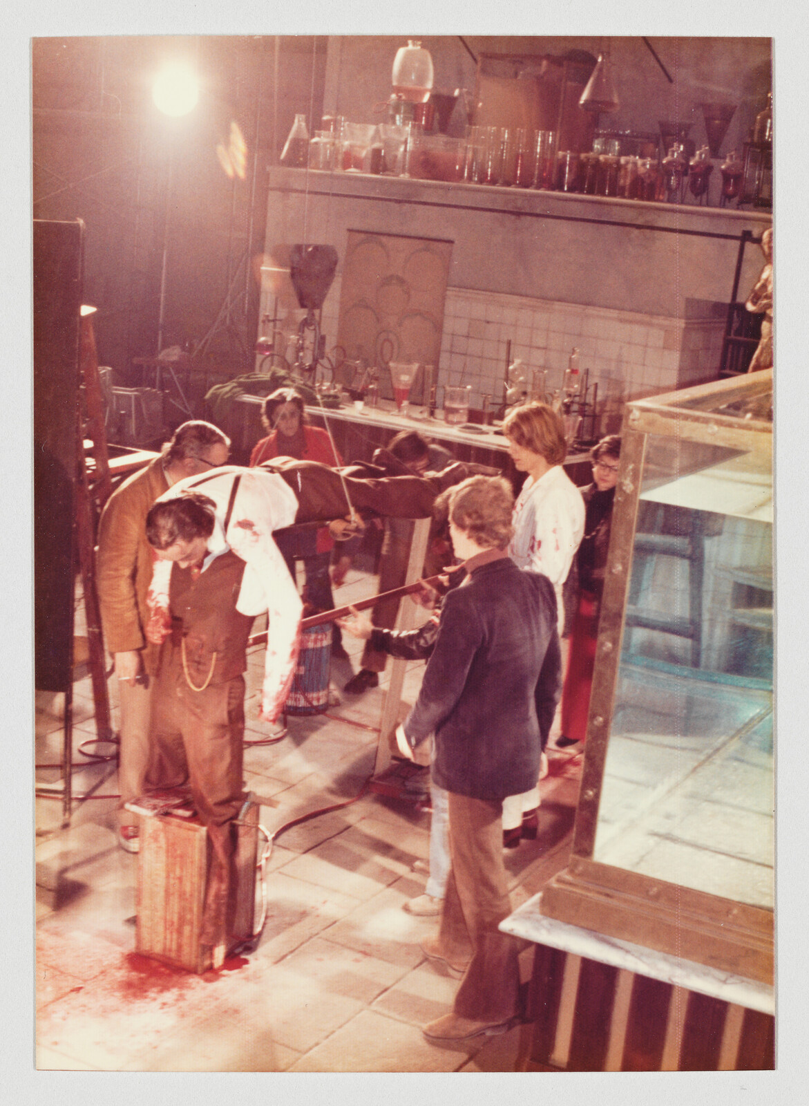 Crew members lift a bloodied man on a makeshift stretcher while others stand nearby.