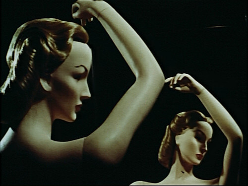 Two vintage female mannequins posed with arms raised against a dark background.