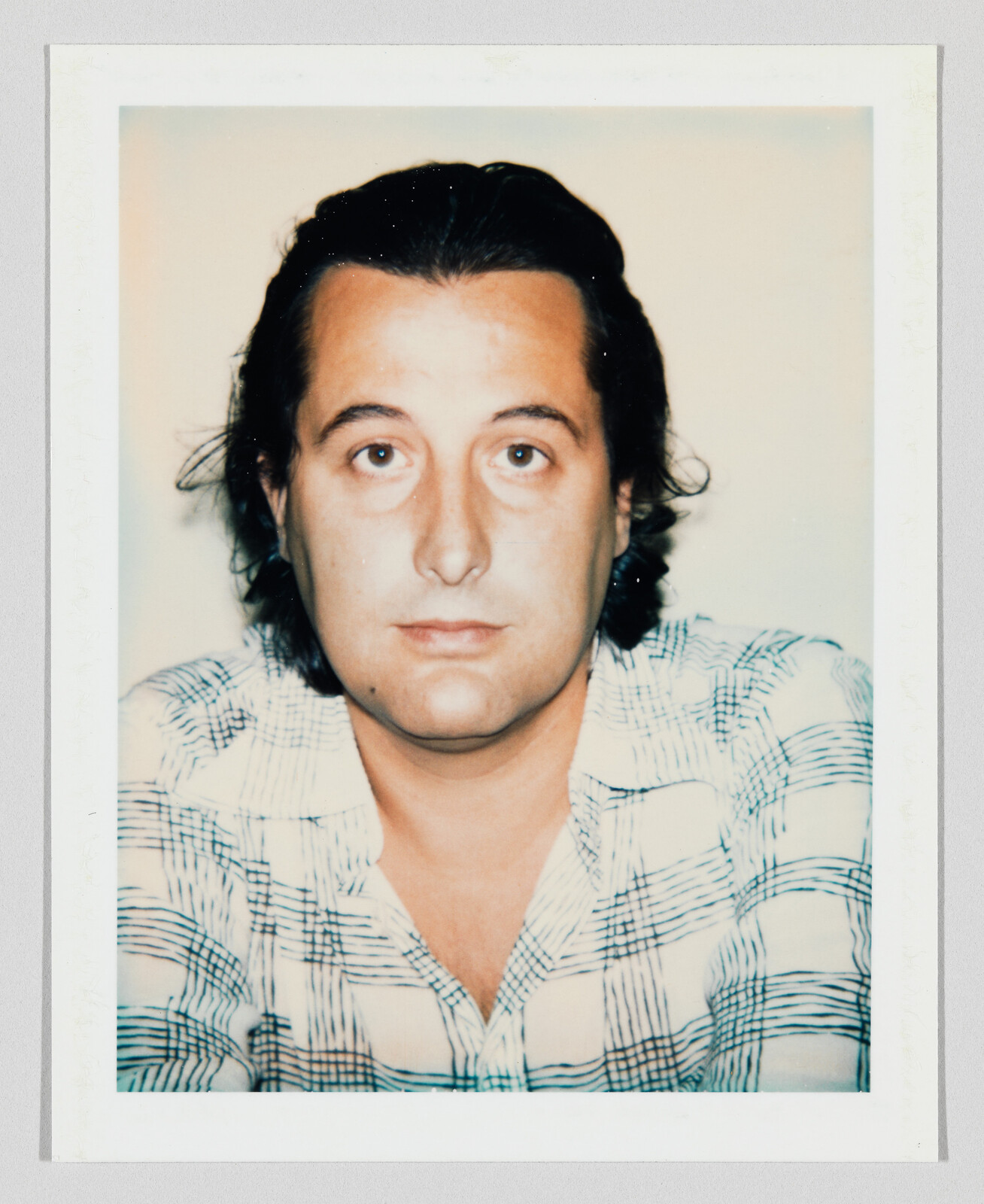 A man with dark hair and a plaid shirt looking directly at the camera.