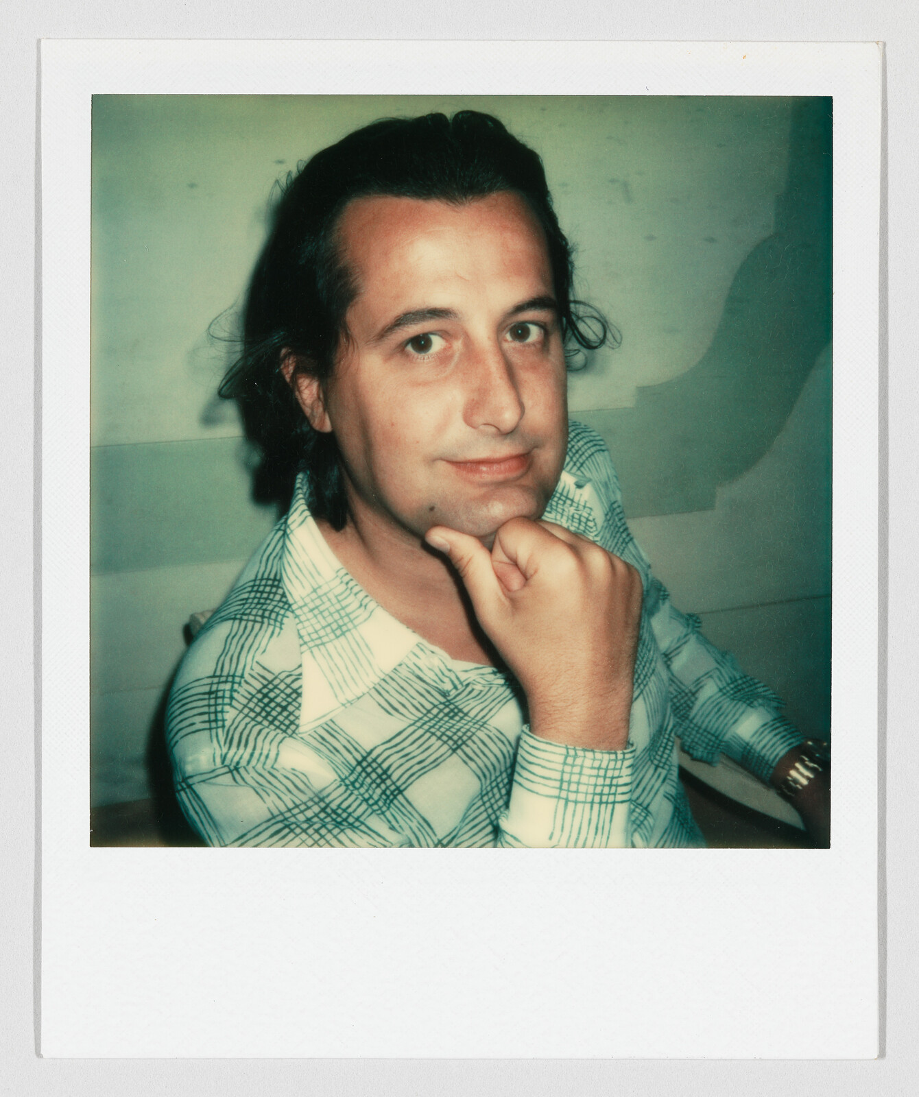 A person looks at the camera while resting their chin on their fist.