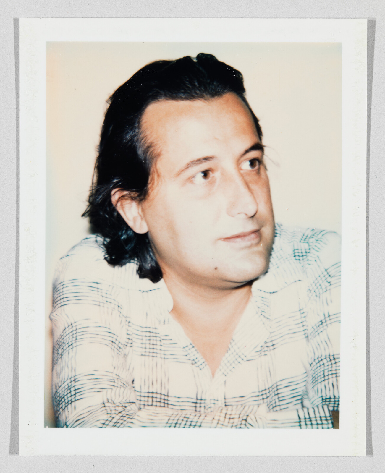 Man with dark hair and checked shirt looking slightly to the right with a calm expression.