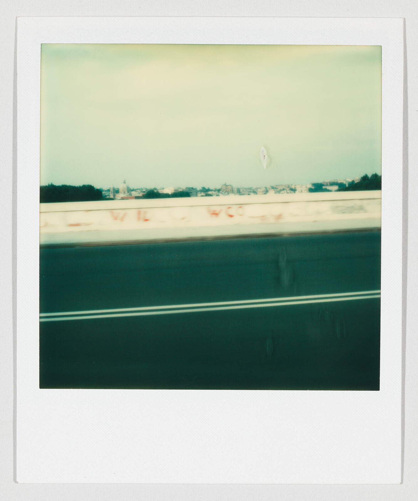 Blurred view of a highway with double lane lines and a graffiti-covered concrete barrier.
