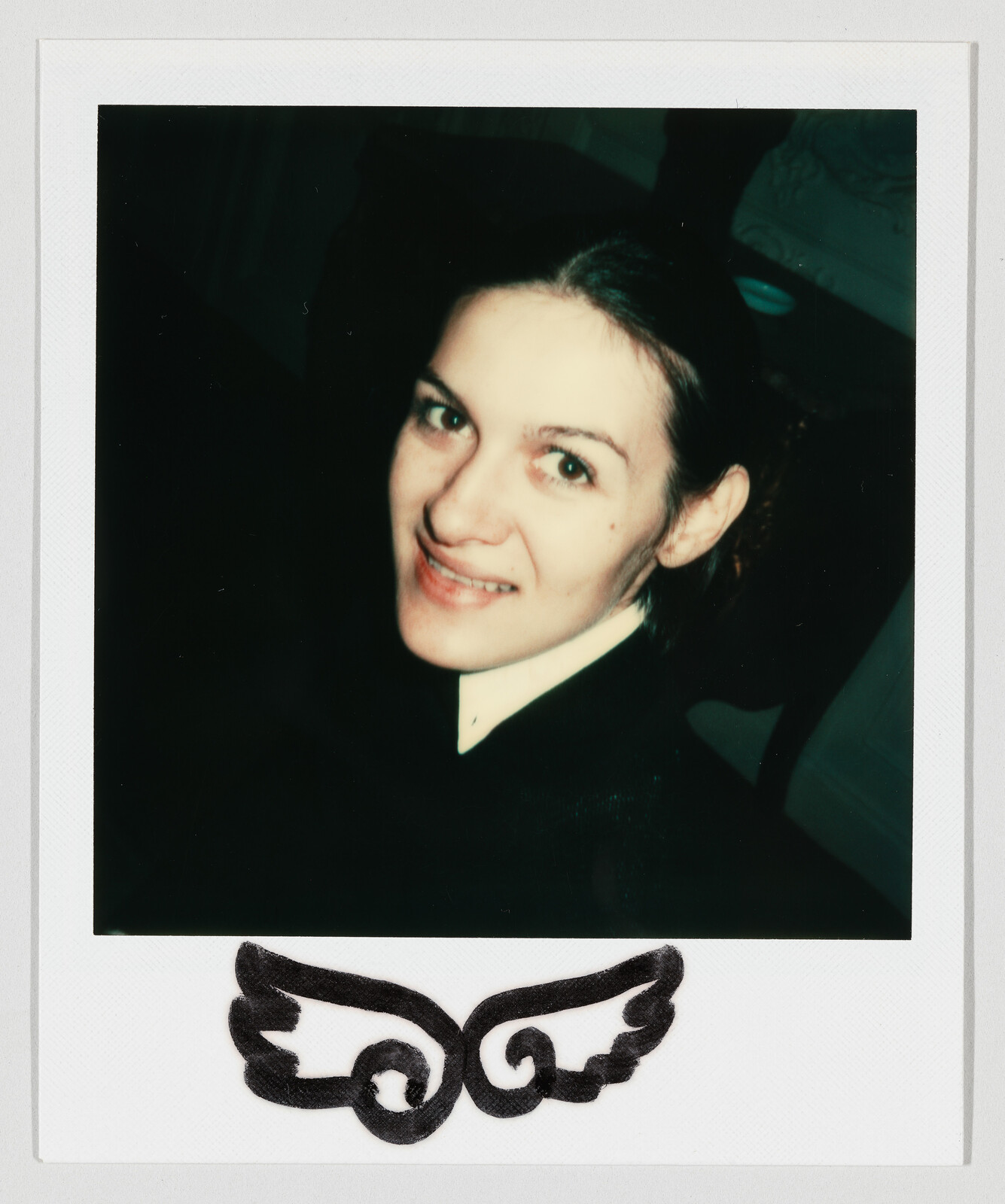 Young woman smiling and looking up toward the camera in a Polaroid-style portrait.