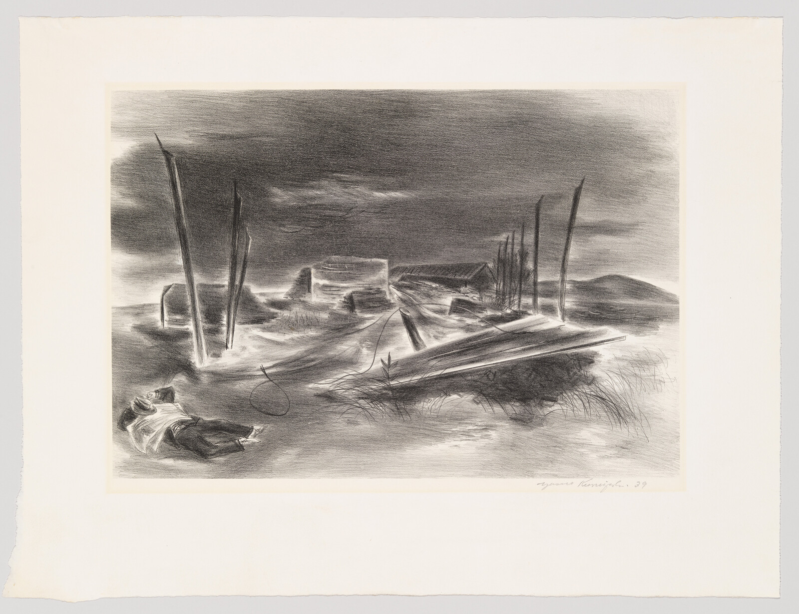 A person lies on sandy dunes near broken wooden planks and tall poles under a dark sky.