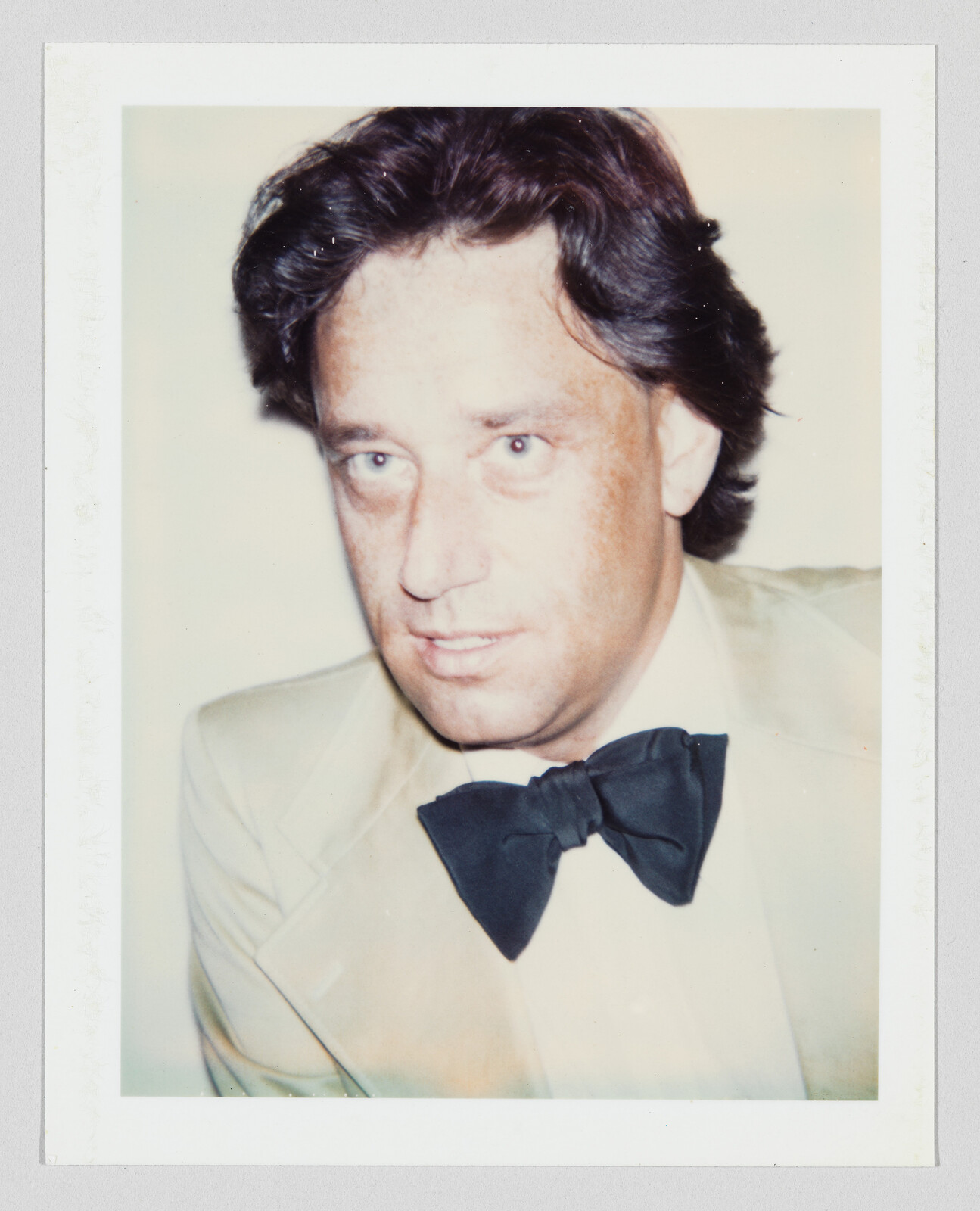 Middle-aged man wearing a light suit and black bow tie looking slightly to the side.