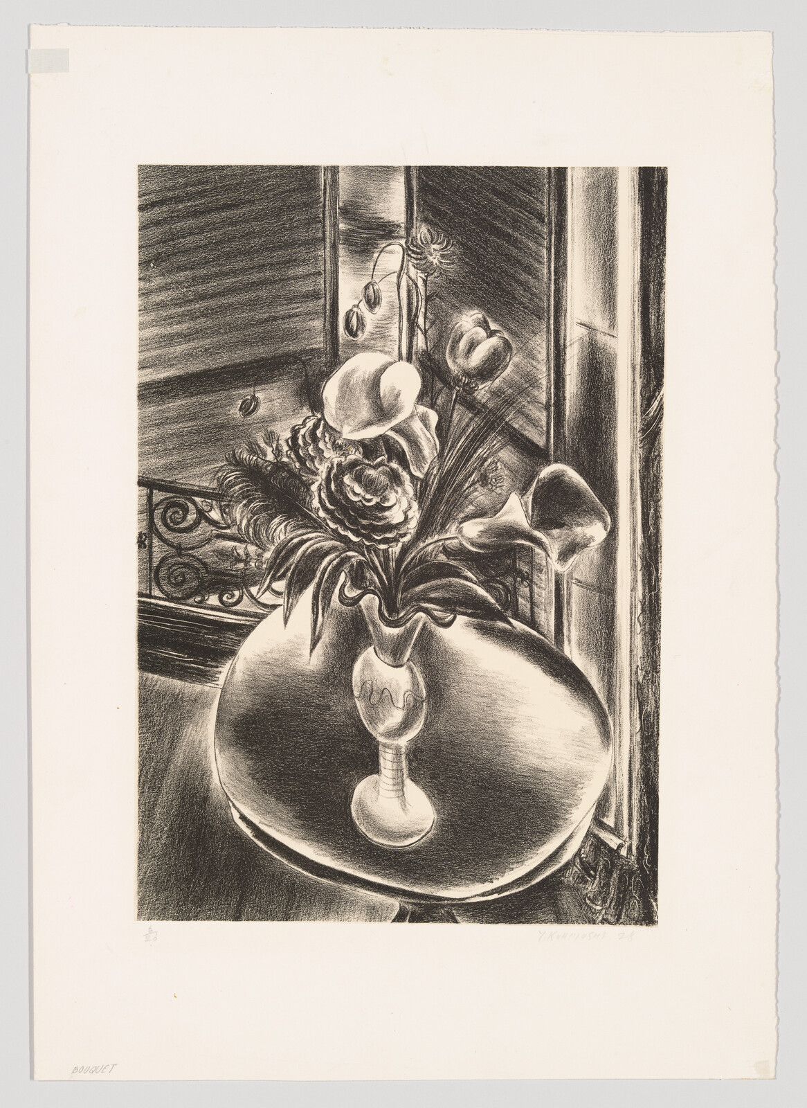 A vase of mixed flowers sits on a round table beside a window.