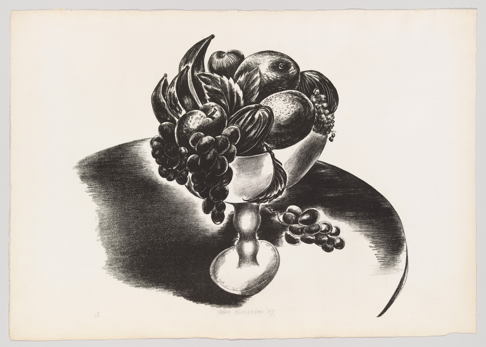 A footed bowl overflowing with grapes, bananas, apples, and other fruit on a table.