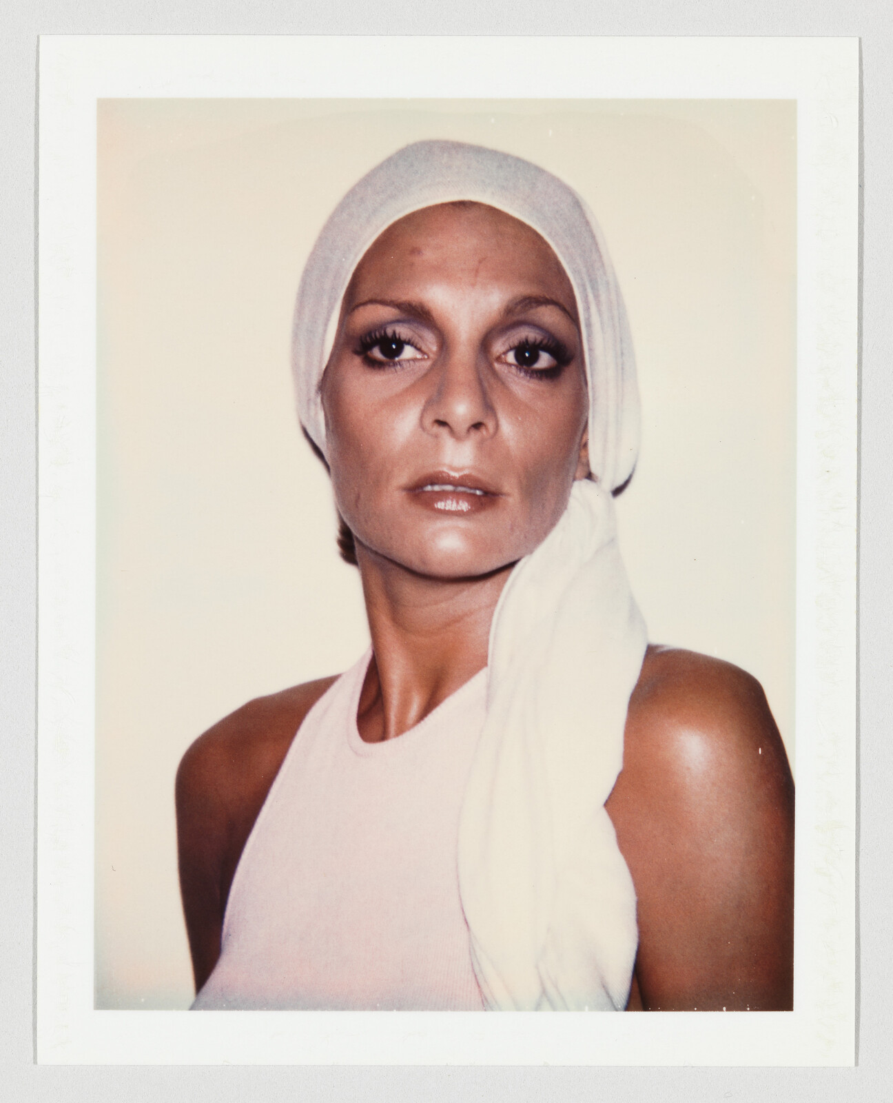 Woman wearing a white headscarf and sleeveless top, looking directly forward with a neutral expression.