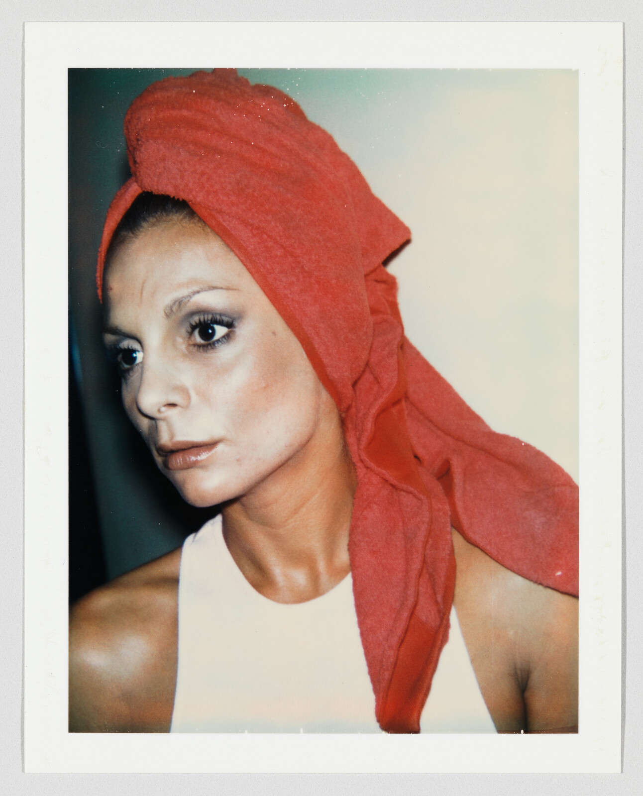 Woman with a red towel wrapped around her head looks off to the left with calm expression.