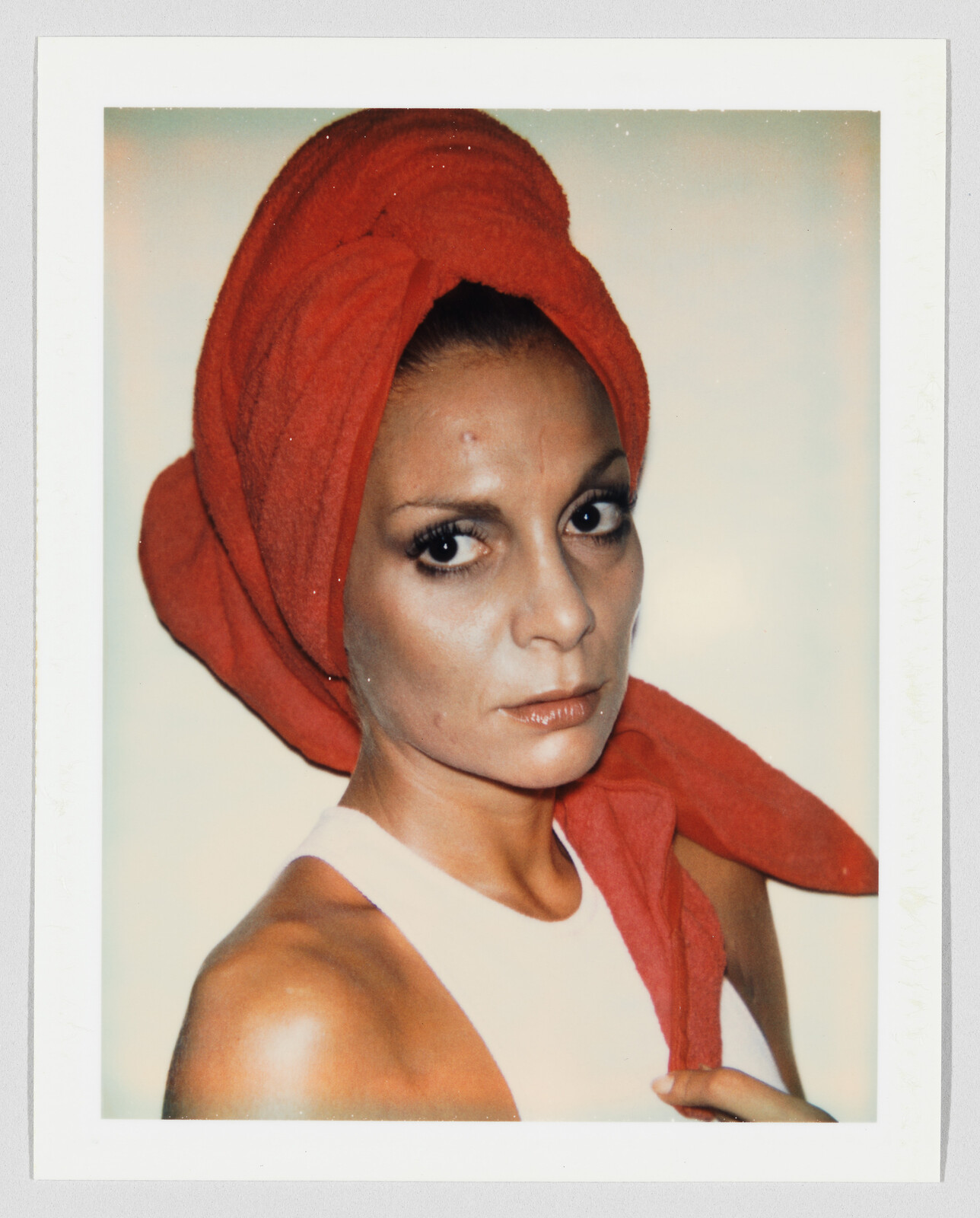 Woman with a red towel wrapped around her head looking directly at the camera.