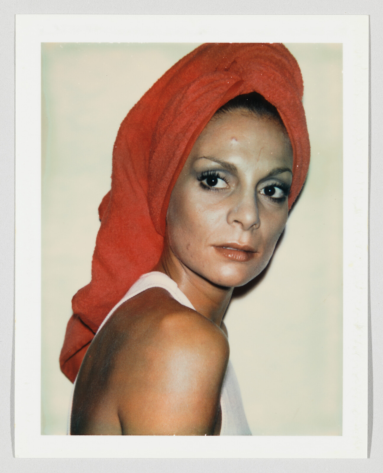 Woman with a red towel wrapped around her head looks back over her shoulder.