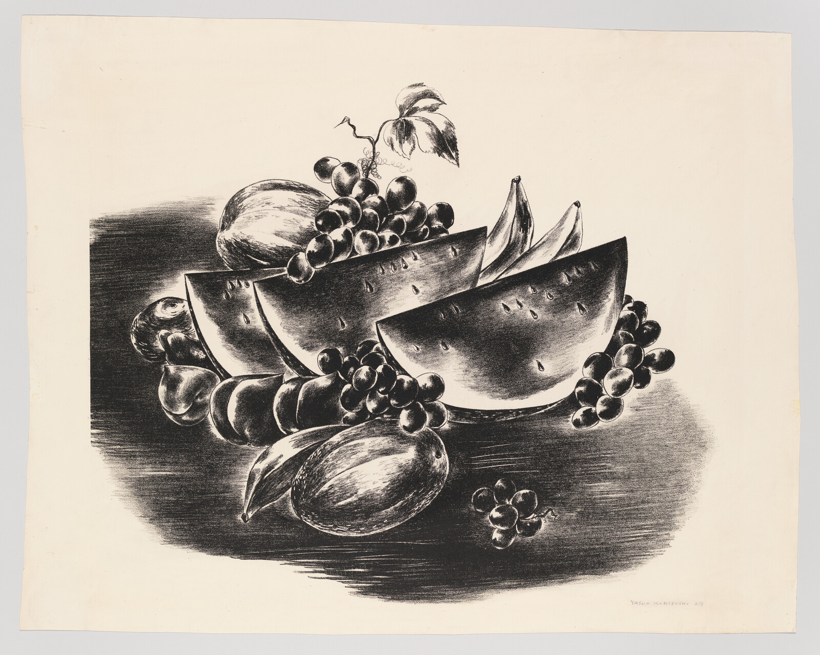 Three watermelon slices surrounded by grapes, bananas, and other fruits on a tabletop.