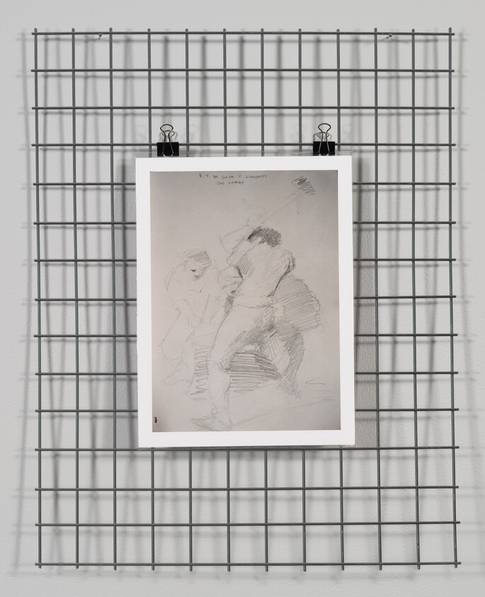 Framed pencil sketch of two standing figures clipped to a metal grid display on a wall.