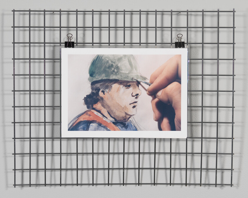 A watercolor portrait of a man in a hard hat clipped to a wire grid.