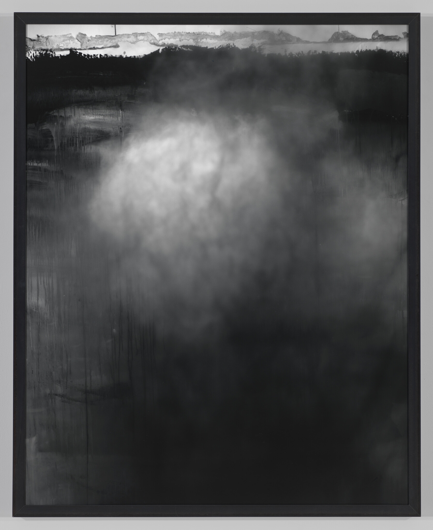 A large framed black-and-white abstract painting showing a diffuse cloudy light area and dark drips.