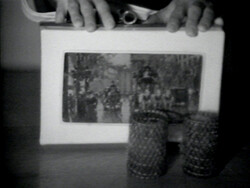 Hands hold a book with a city street picture on the cover; two textured cups sit in front.