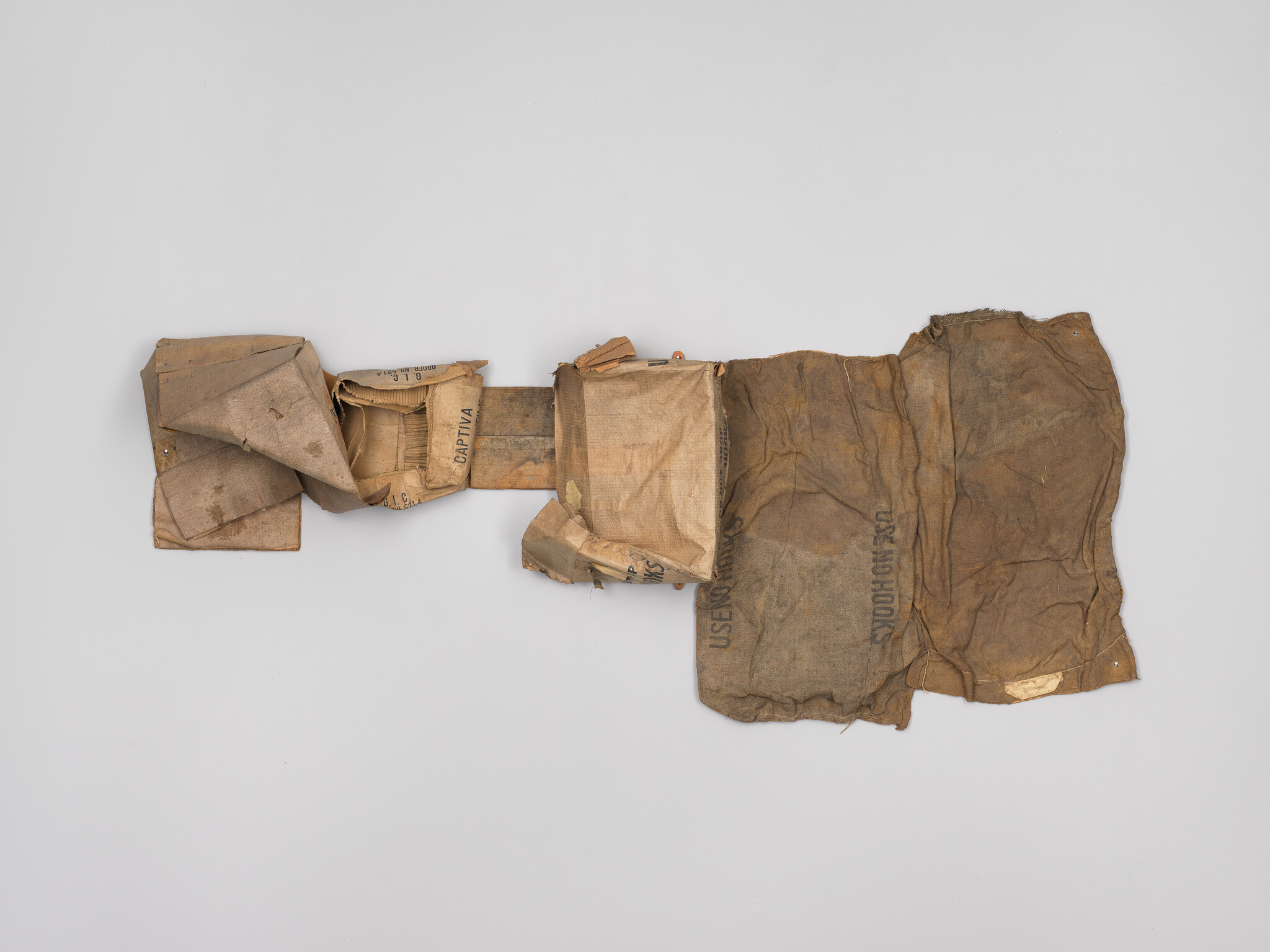 Worn, patched canvas and burlap sacks arranged flat with folded pockets and faint stenciled text.