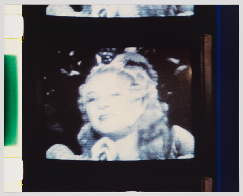 A vintage television screen shows a close-up of a smiling woman with long wavy hair.
