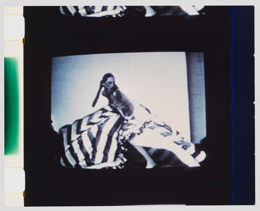 Woman in a large striped skirt spins on a small screen, captured in black-and-white.