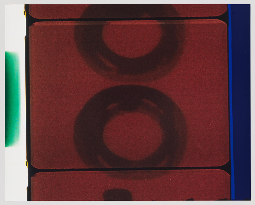 Close-up of a red film strip showing two dark circular frames and colored edges.
