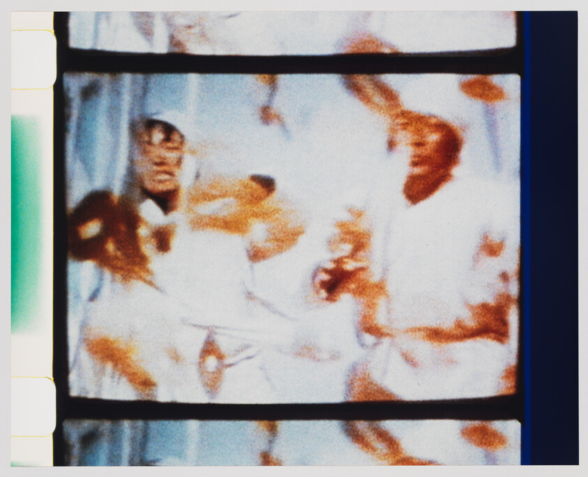 A blurry and distorted image of a person, possibly from a video or film, with warm color tones and visible scan lines indicating it may be a still from an older television or monitor.