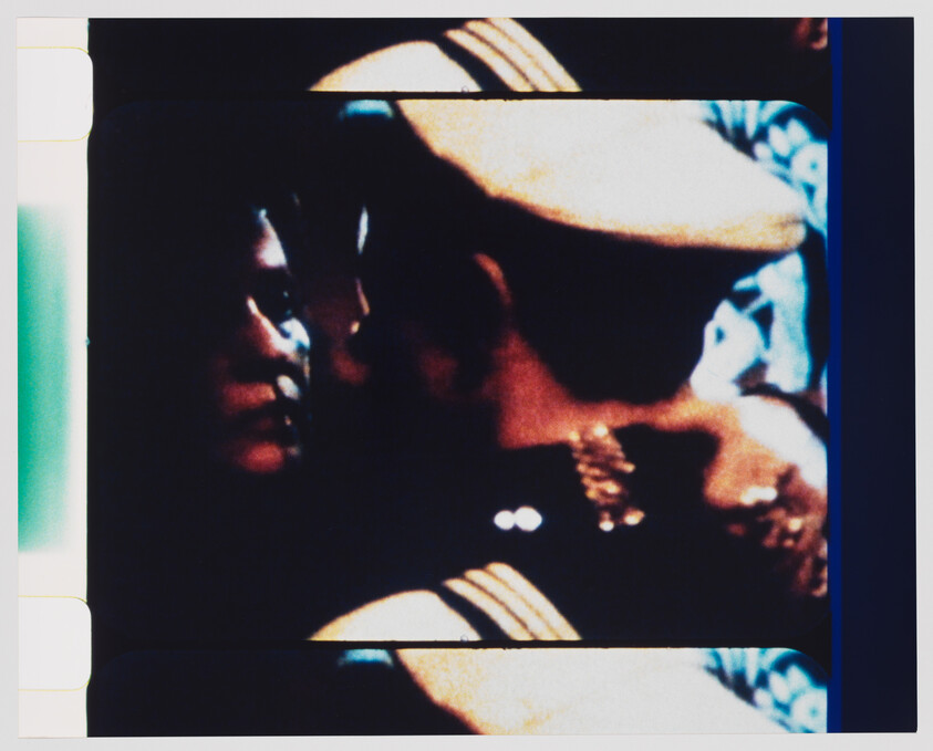 A close-up of two people embracing with their faces nearly touching in dim, grainy light.