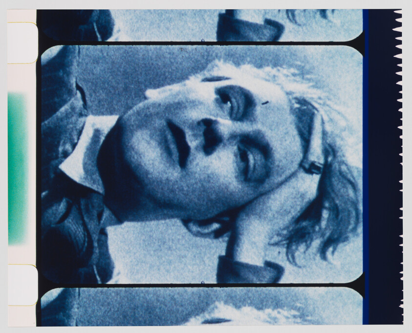 Young person reclining with hand behind head, eyes partly closed in a blue-tinted film frame.