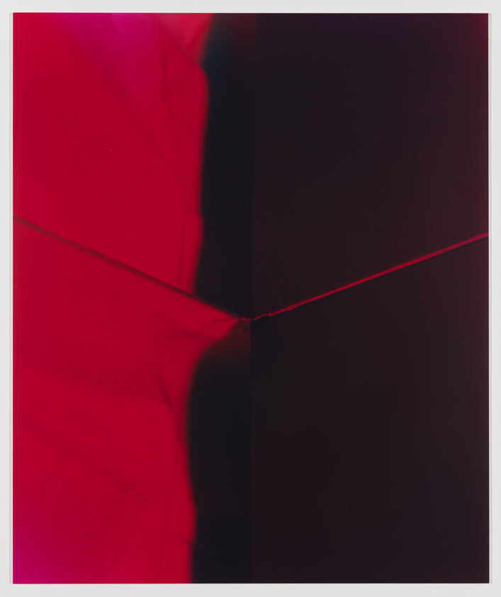 A red and dark panel meet at the center with a thin diagonal seam and small knot.