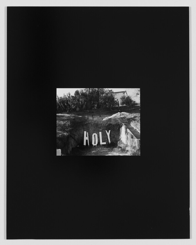 Large letters spelling "HOLY" stand on a hillside near stairs and trees.