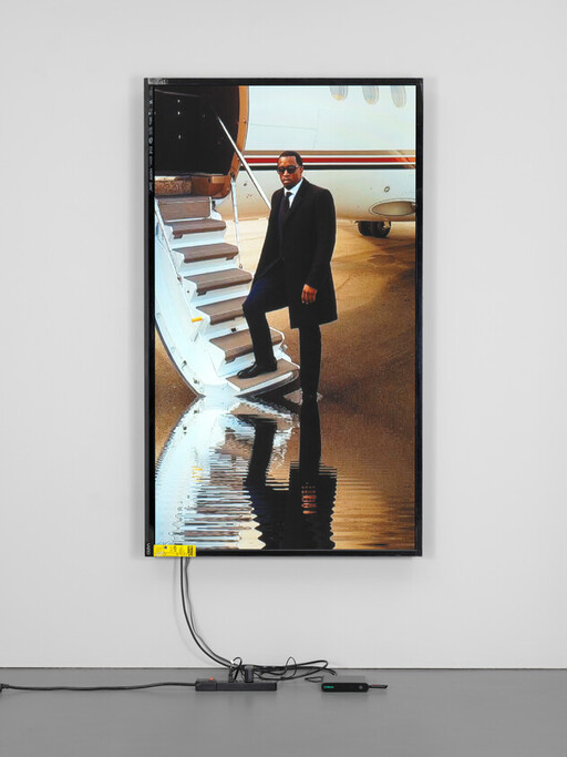 A man in a suit stands on jet stairs with his reflection visible in water.