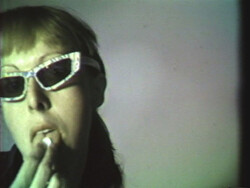 Person wearing sunglasses touches their mouth with their fingers, looking slightly to the side.