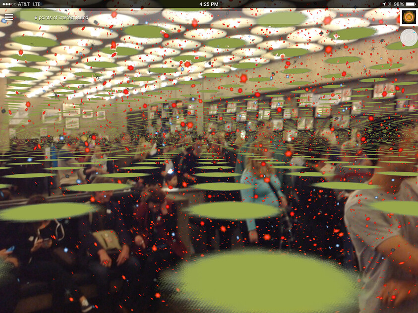 Crowded room with people using phones, overlaid with digital effects of green circles and red dots, creating a virtual reality feel.