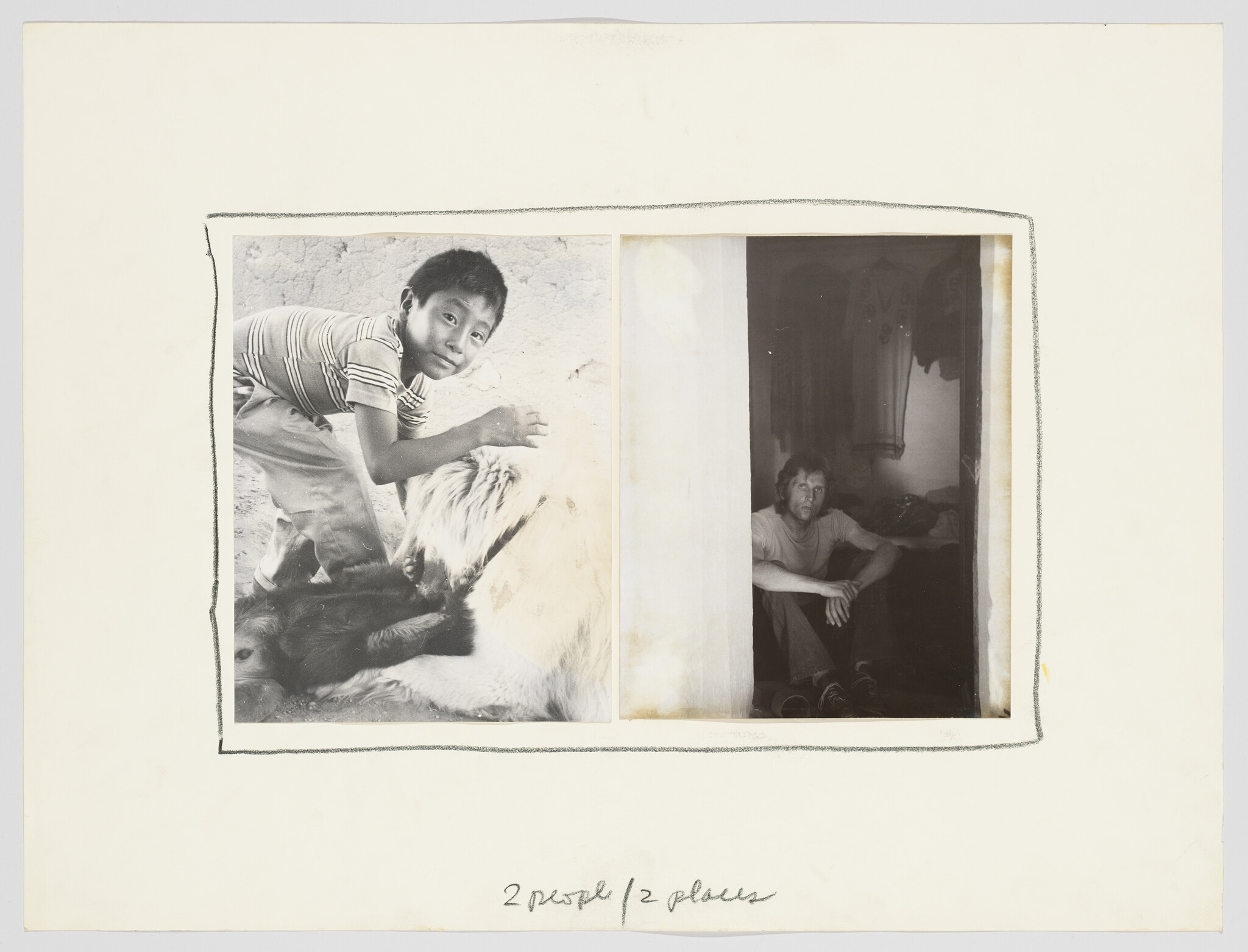 A boy pets a large dog outdoors while a man sits inside a dark doorway.