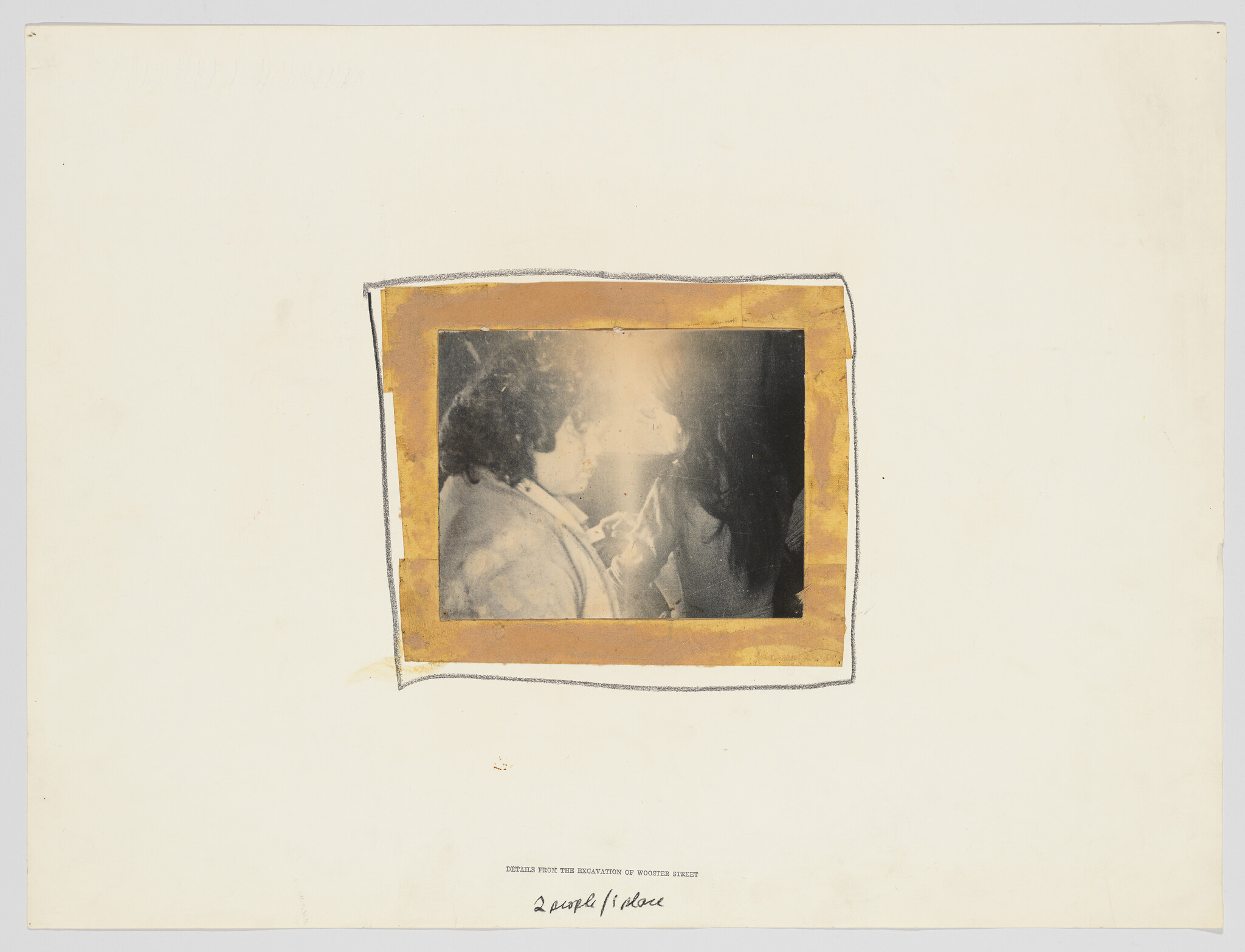 Two people face each other closely in a small faded photograph mounted on white paper.