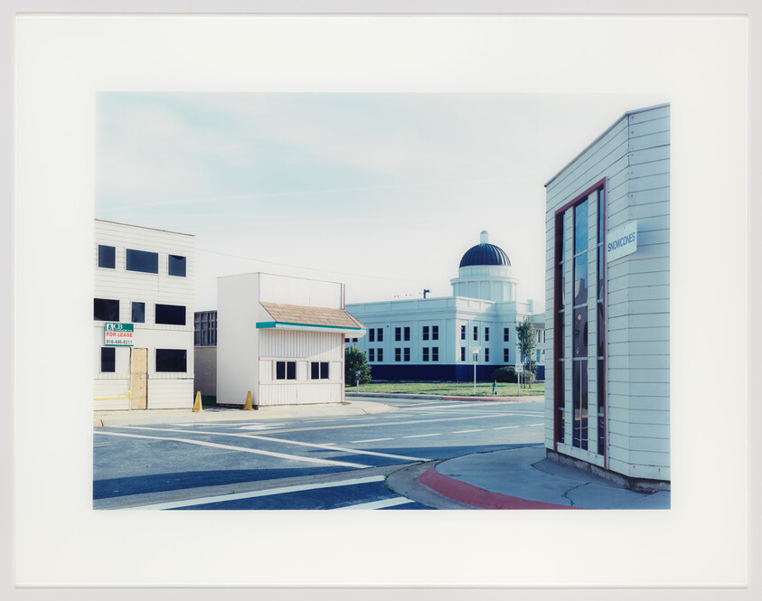 Small storefronts and an empty intersection with a domed civic building in the background.