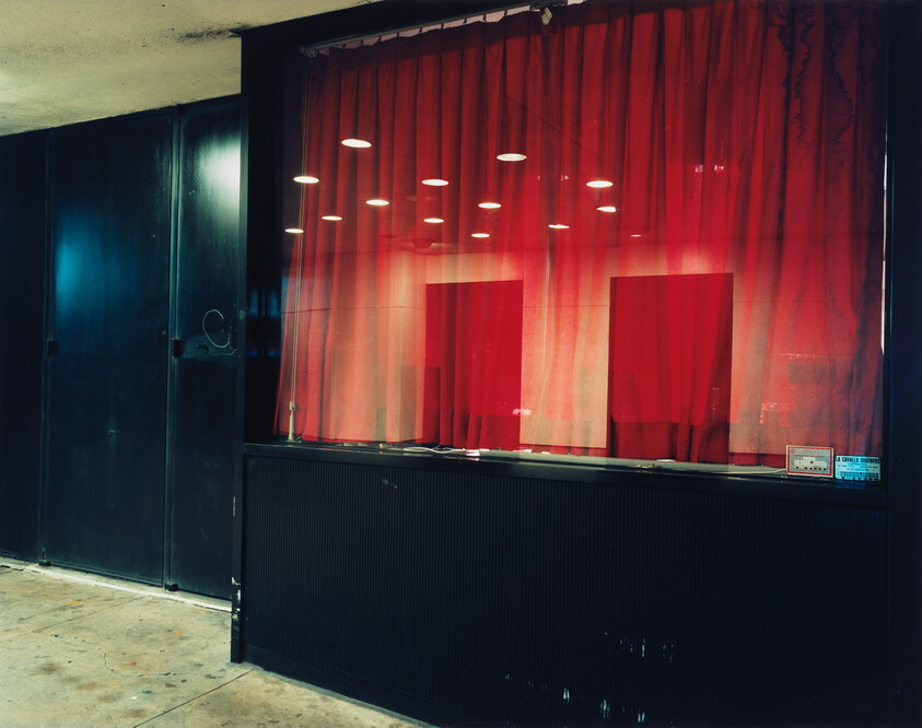 Red curtains with spotlights behind a glass window, creating a theater-like display.