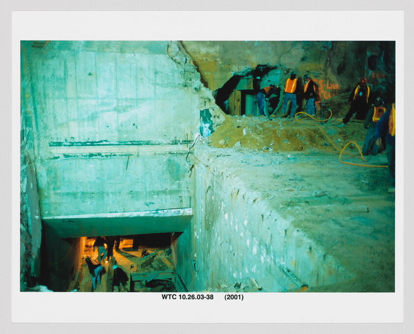 Rescue and recovery workers in safety vests examine a large concrete excavation at the WTC site.