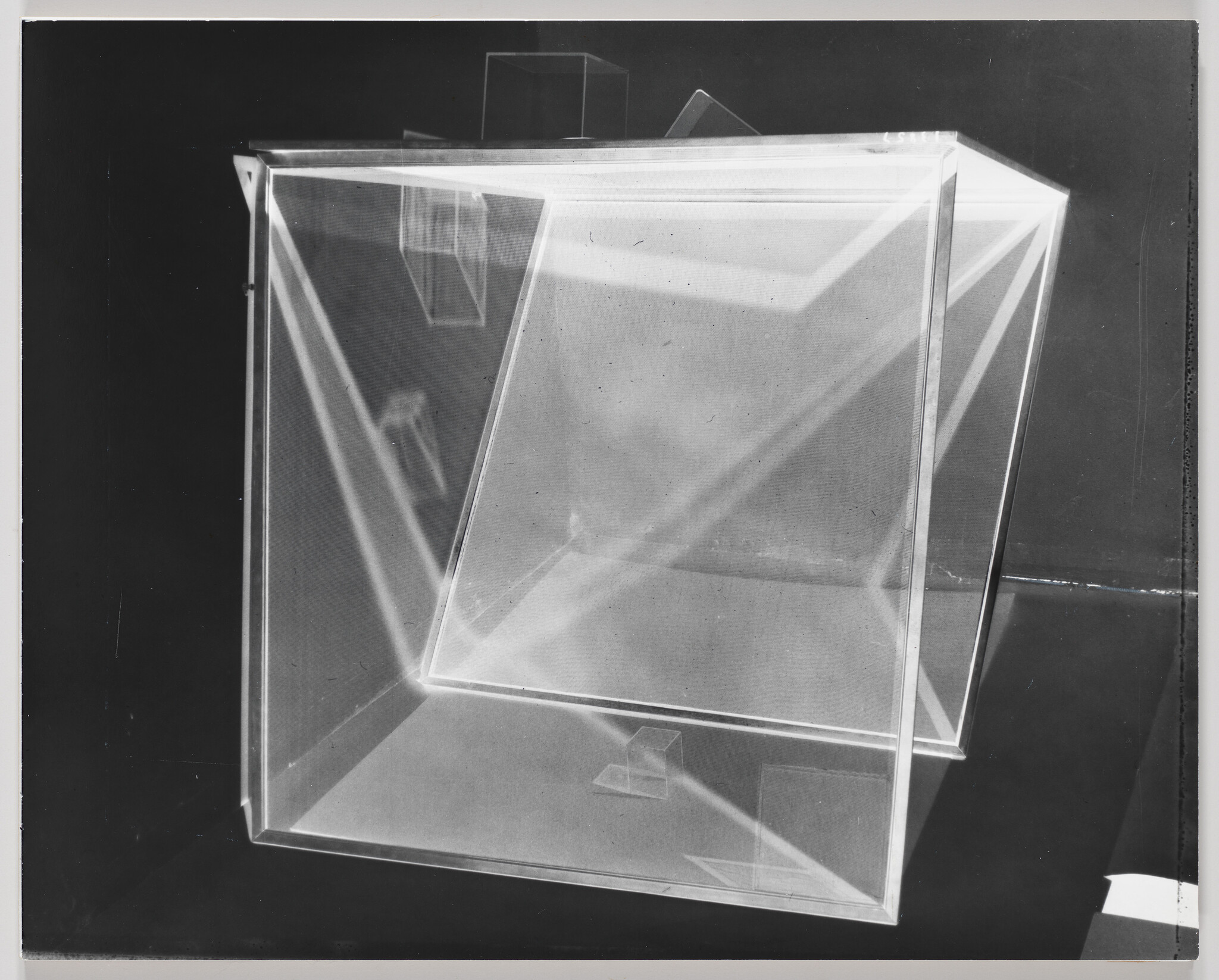 A tilted translucent cube suspended inside a larger clear cube showing light reflections.