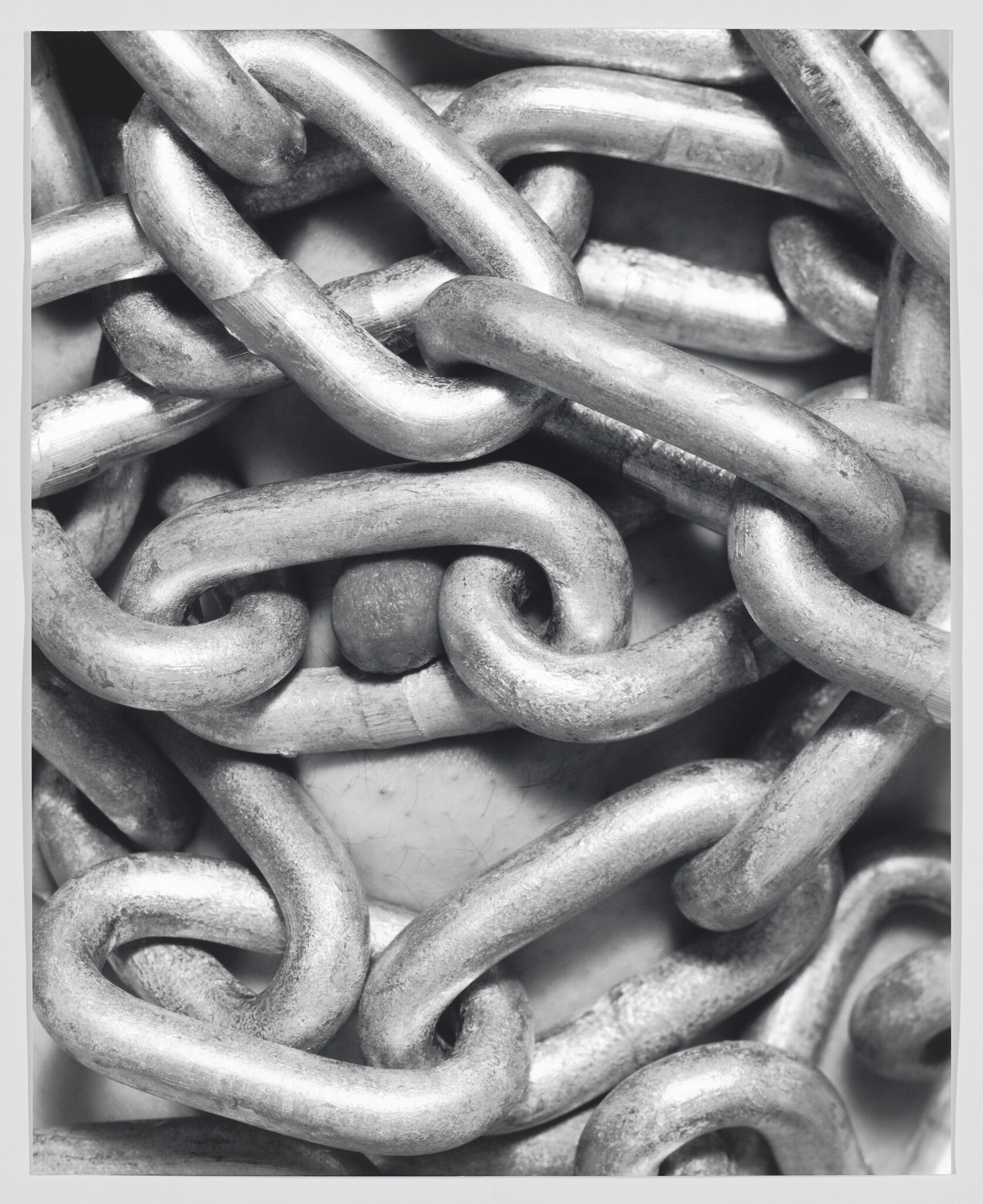 Thick metal chains densely cover a face, leaving only part of the nose visible.