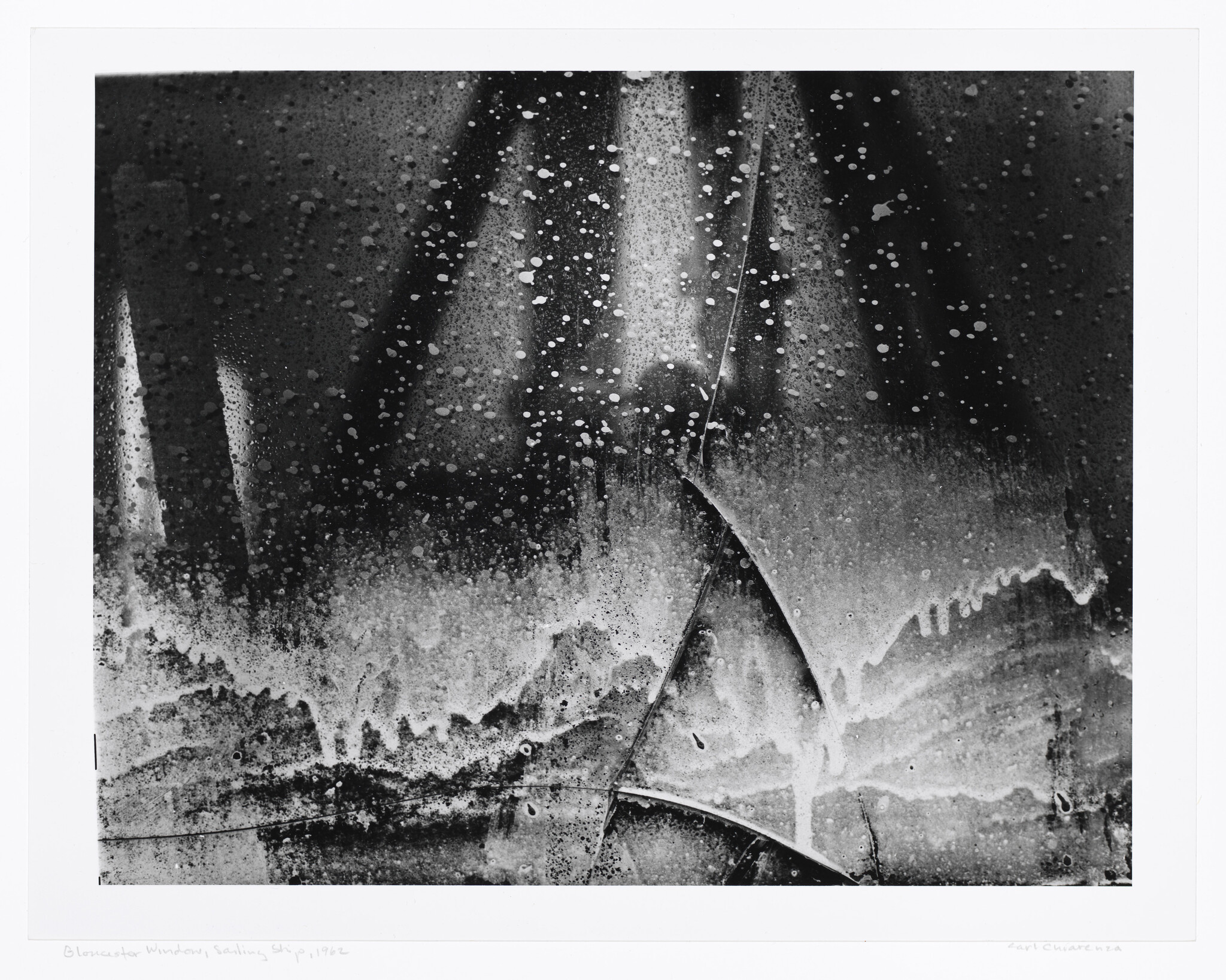 Condensation and streaks cover a cracked black-and-white surface, with scattered water droplets.