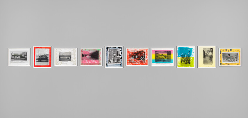 A horizontal row of ten framed artworks with colorful borders hung on a gray wall.