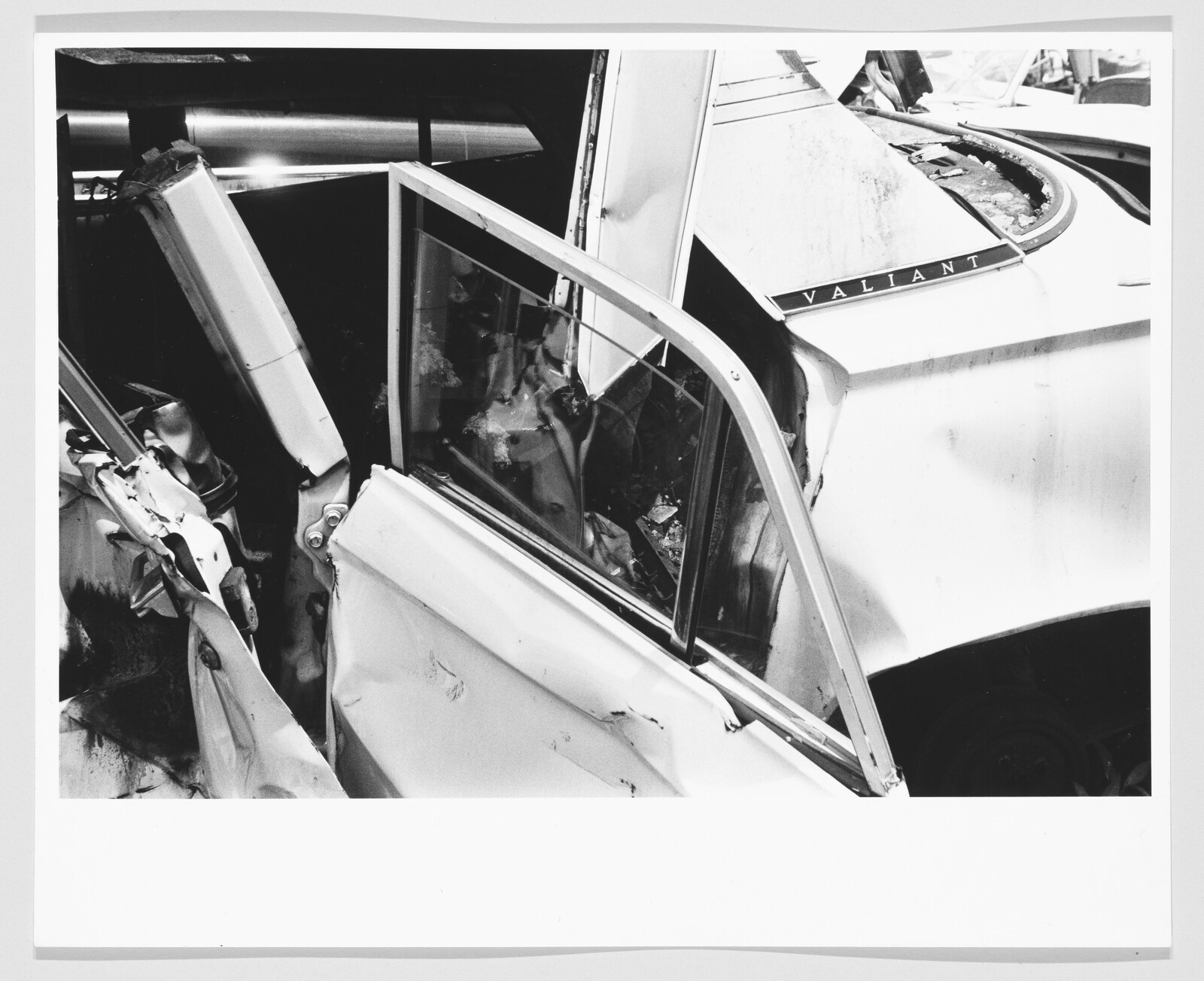 A severely crumpled car door and frame show collision damage with the Valiant badge visible.