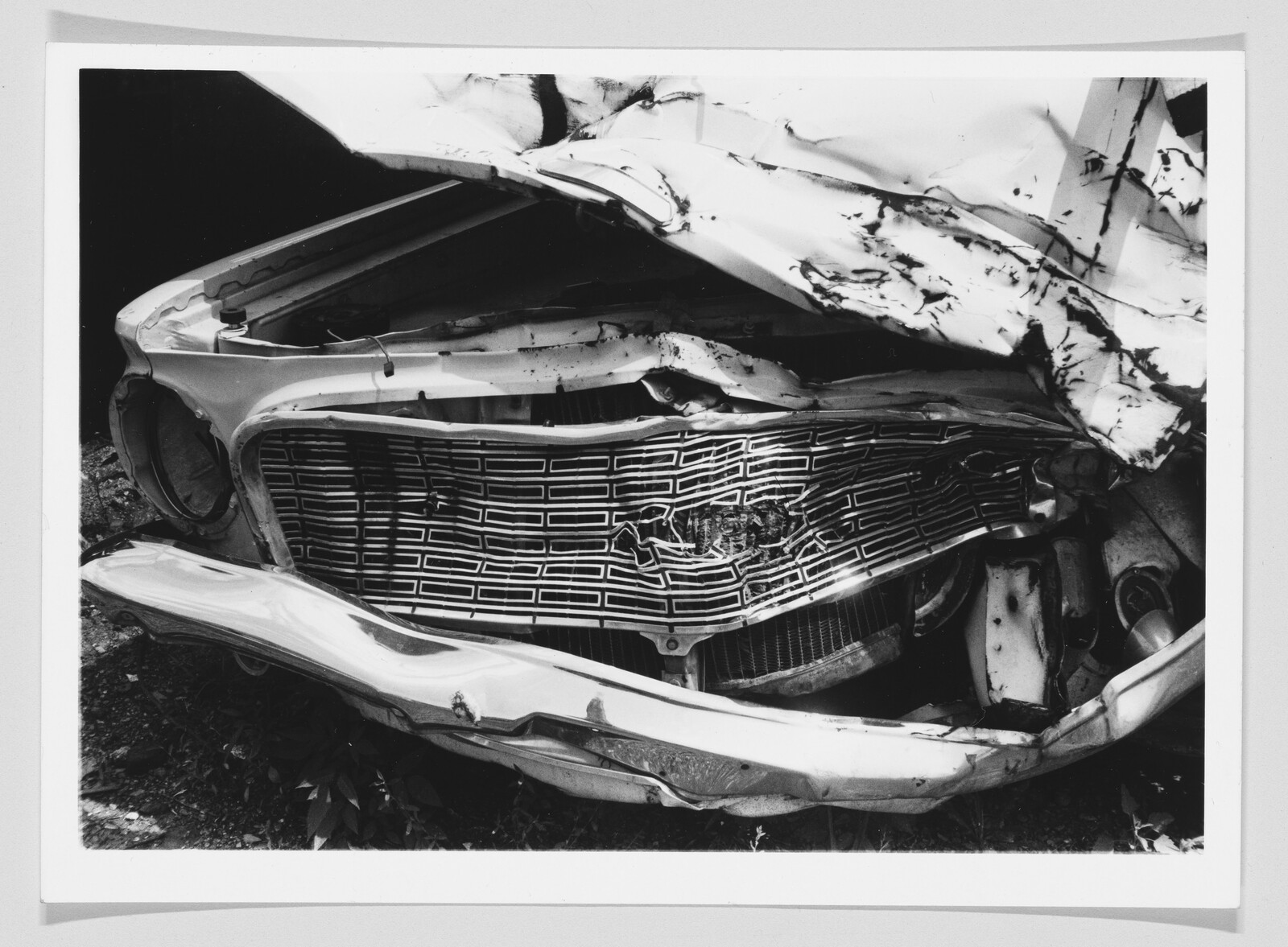 Front of a car with a crumpled grille and bent bumper from a severe collision.