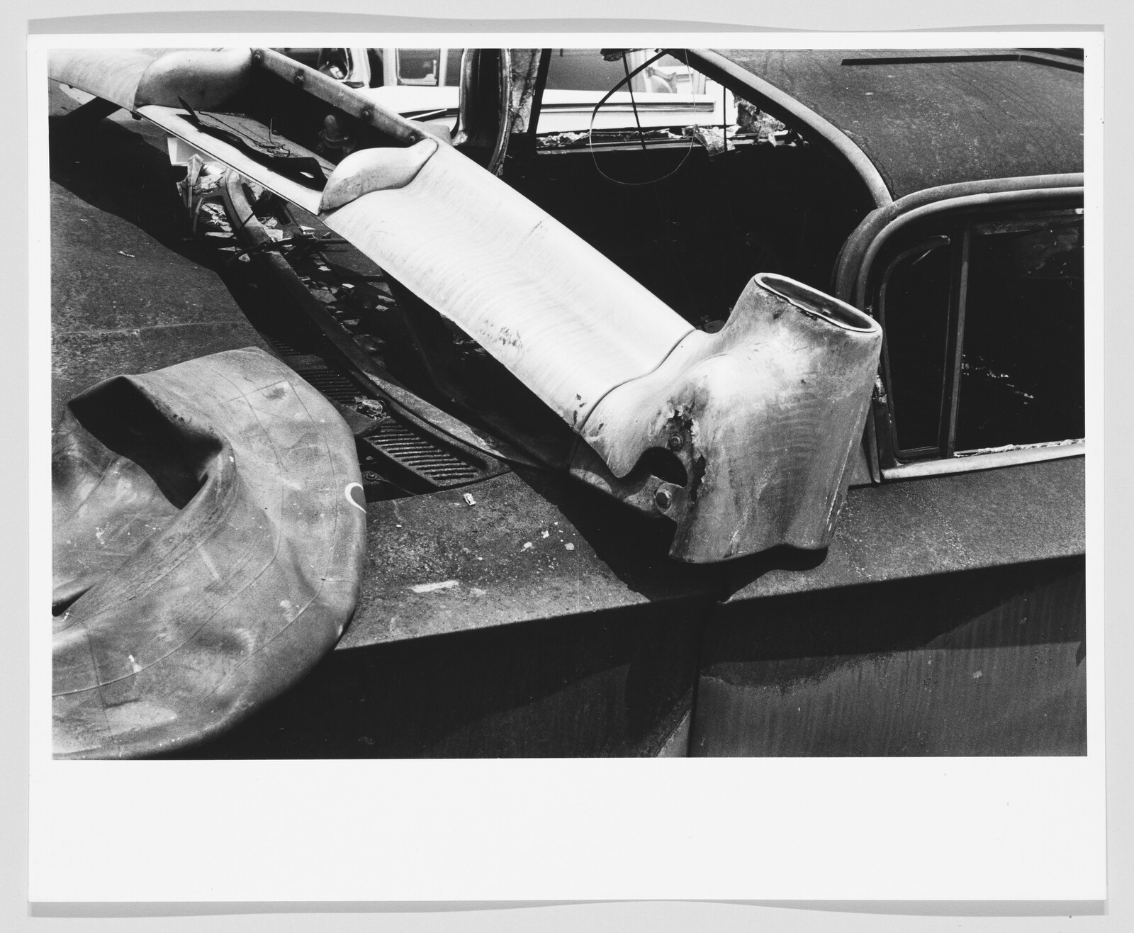 Large dented car fender and a deflated tire tube resting on a damaged vehicle roof.