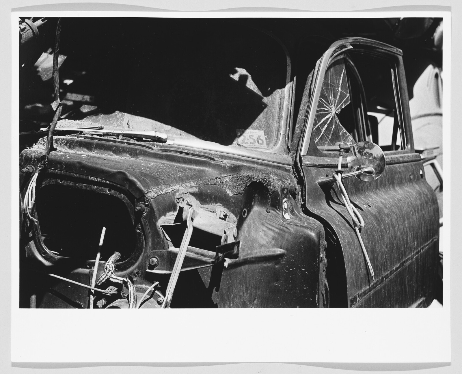 Rusty truck door with cracked window, missing headlight, and exposed wires near the fender.