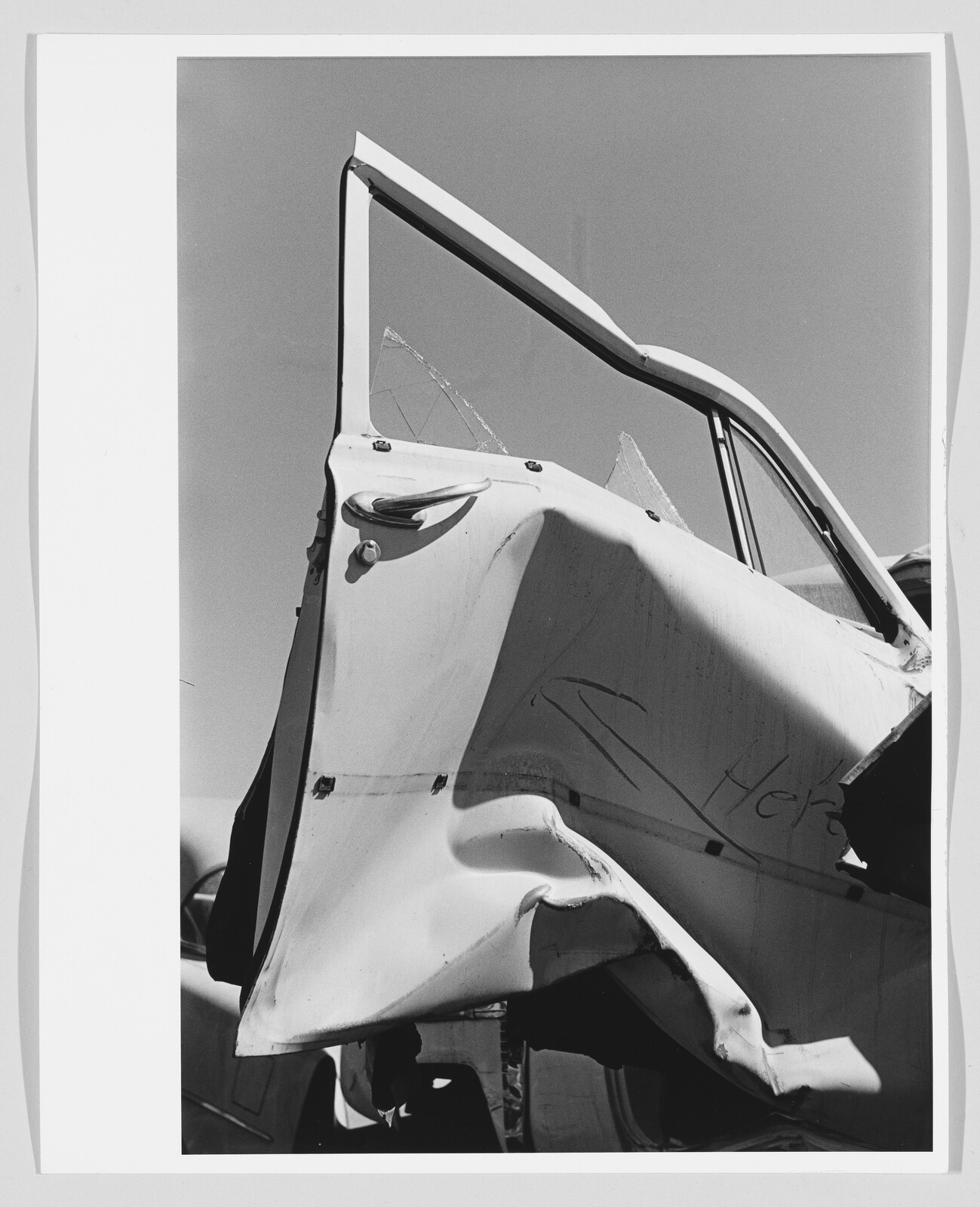 A severely dented car door is open with shattered window glass visible.