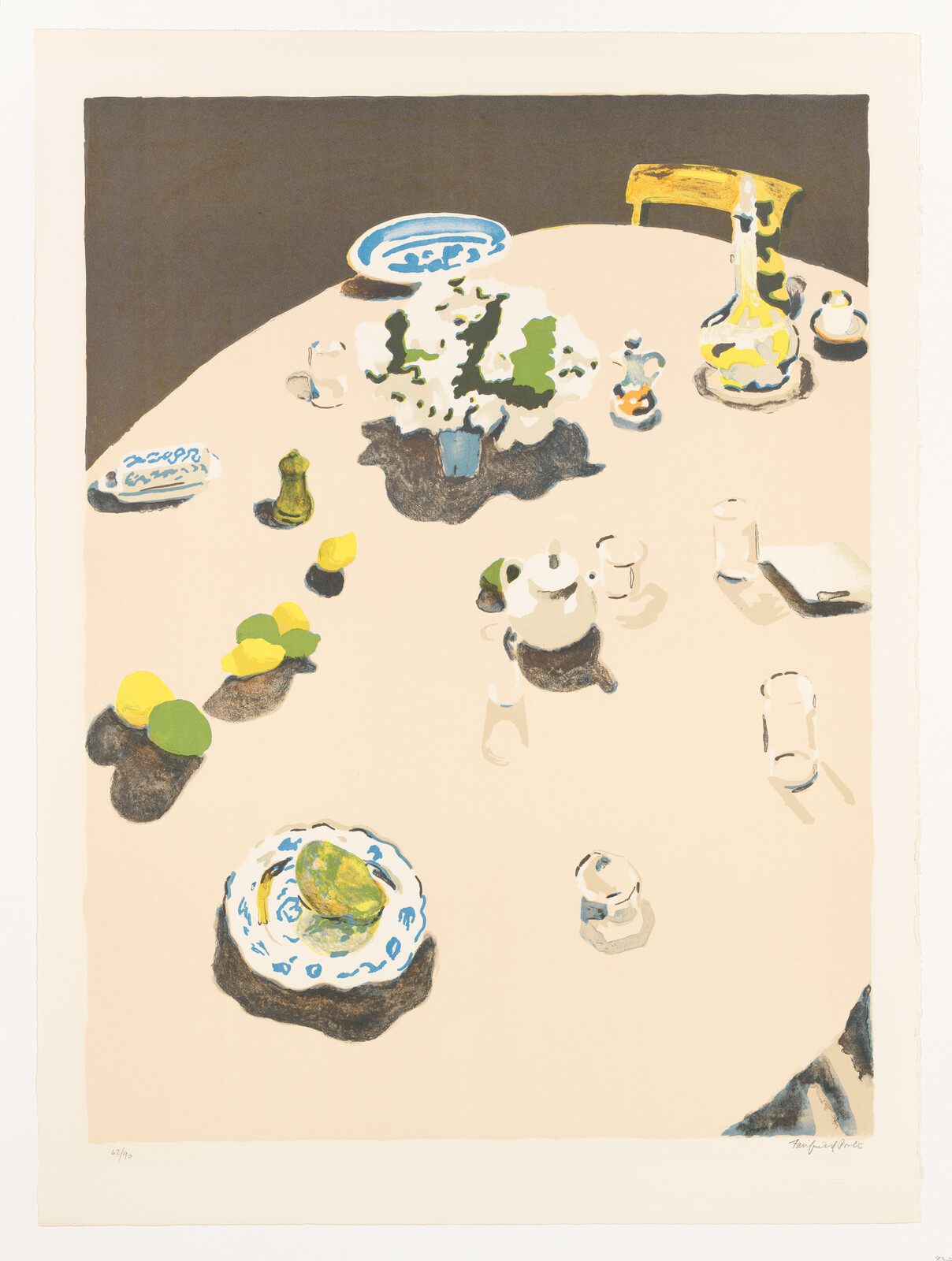 A round table set with a vase of white flowers, teapot, pitcher, plates, and fruit.
